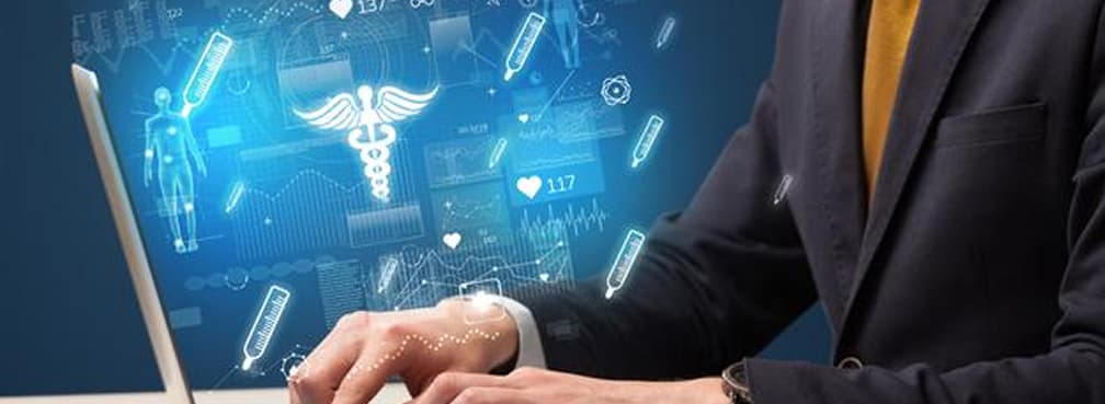 Close-up of hands typing on a laptop showing a caduceus healthcare graphic.