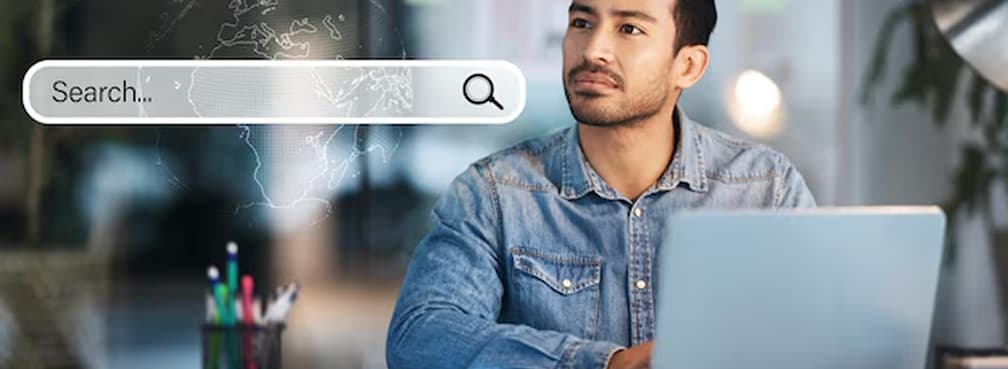 Man using a laptop with a floating digital search bar graphic, representing SEO or research.