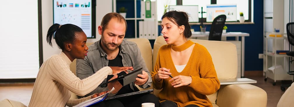 Close-up of teammates reviewing data and sharing ideas on a digital tablet.