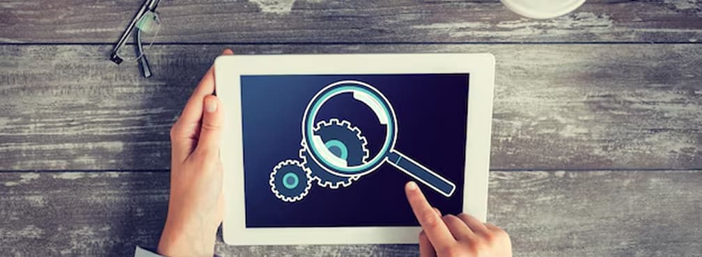 A top-down shot of a tablet screen featuring gears and a magnifying glass graphic.