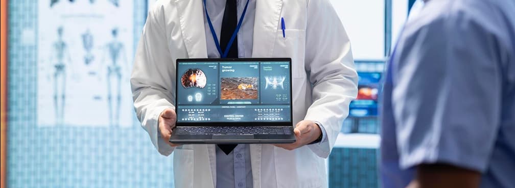 Close-up of a clinician presenting medical imaging and diagnostics on a laptop.